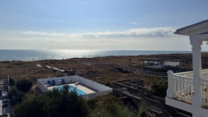A pool area with a view of the beach and ocean. - Majak Moments 7 Bedroom Home by RedAwning (Supply)