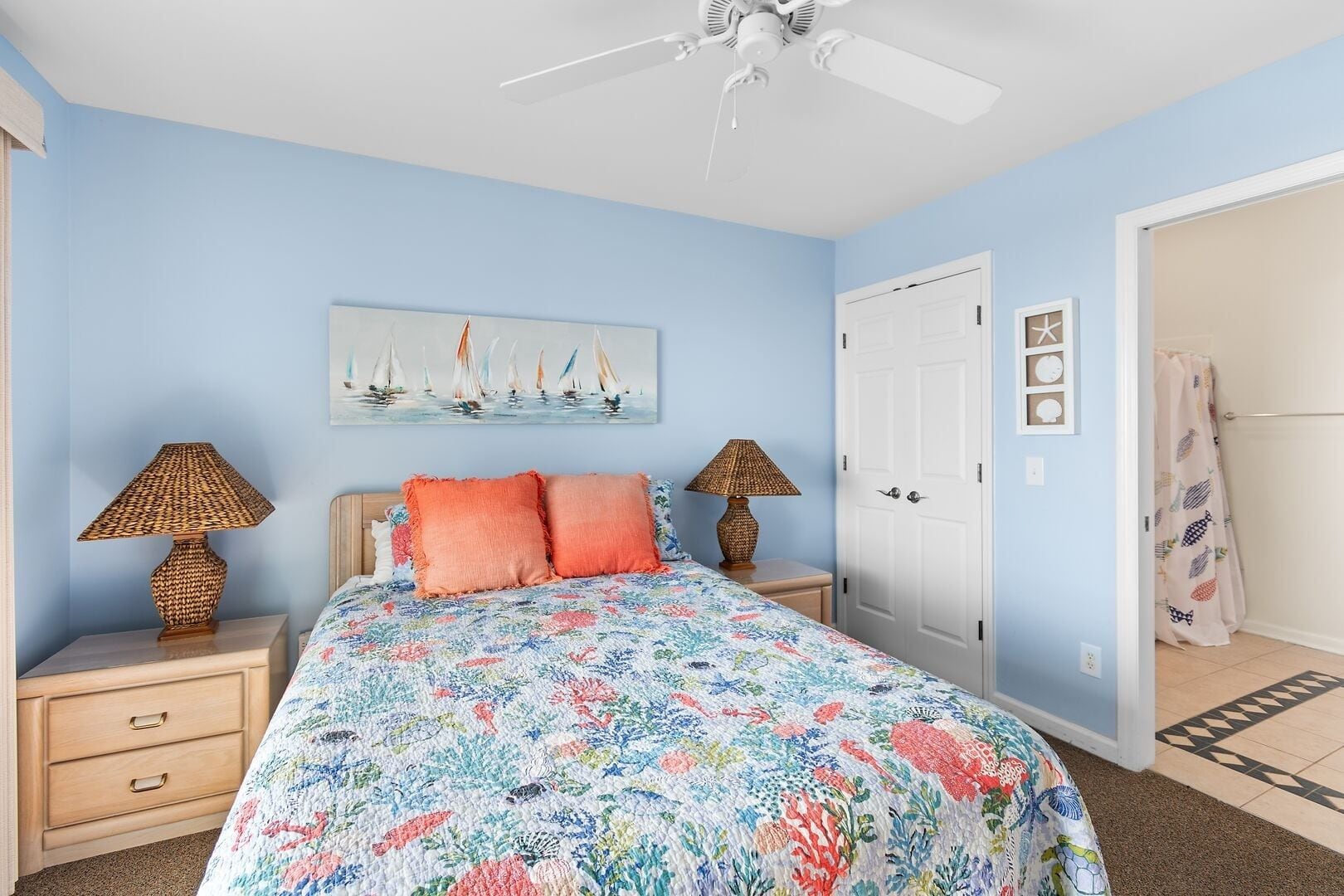 A bedroom with a bed, two nightstands, a ceiling fan, a door, and a wall with a painting.