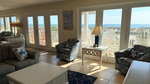 A spacious living room with a view of the beach, furnished with a sofa, chairs, and a coffee table. - Majak Moments 7 Bedroom Home by RedAwning (Supply)
