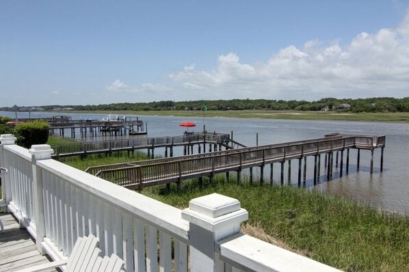 A waterfront property with a wooden dock, a white fence, and a grassy area.