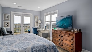 A bedroom with a large bed, a dresser, a desk, and a television. - Ohana - 4 Br Home (Supply)