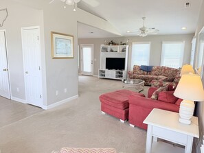 A spacious living room with a red sofa, a television, and a ceiling fan.