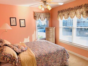 A bedroom with a bed, a dresser, a lamp, and a window with blinds. - Old Man & The Sea 5 Bedroom Home by RedAwning (Supply)