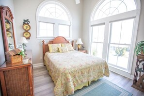 A bedroom with a large bed, two bedside tables, a mirror, and a window with a view. - Paw-paw's Place 6 Bedroom Home by RedAwning (Supply)