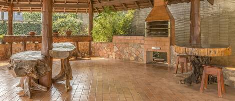 Un patio al aire libre con suelo de ladrillo, mesas de madera y una pared de piedra.