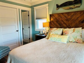 A bedroom with a bed, a nightstand, a lamp, and a wall-mounted decoration. - Raising The Bar 5 Bedroom Home by RedAwning (Supply)