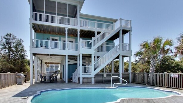 A multi-story building with a pool, outdoor seating, and a covered area.