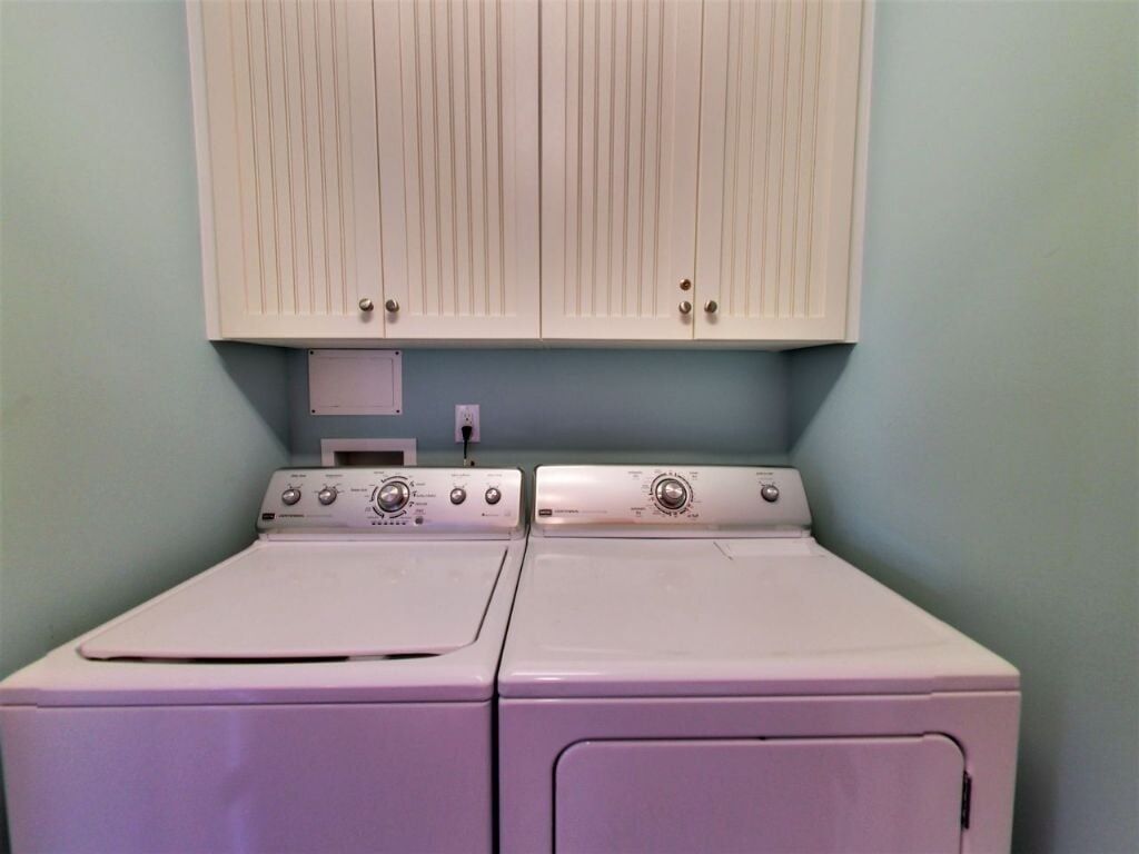A laundry room with two front-loading washing machines and a cabinet above.