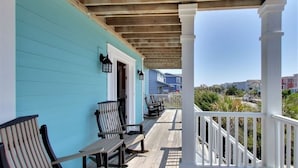 A wooden deck with benches, a covered porch, and a view of neighboring houses.