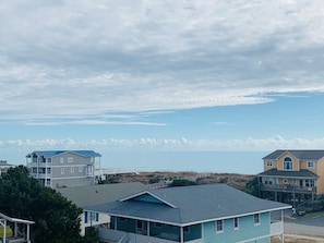 A coastal residential area with houses, a beach in the background, and a clear sky.