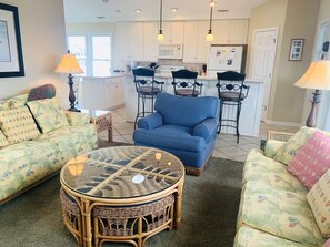 A living room with a blue sofa, a wicker coffee table, and two armchairs.