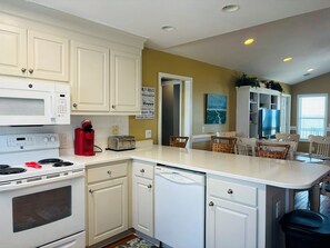 A kitchen with white cabinets, a stove, a microwave, a toaster, and a dishwasher.