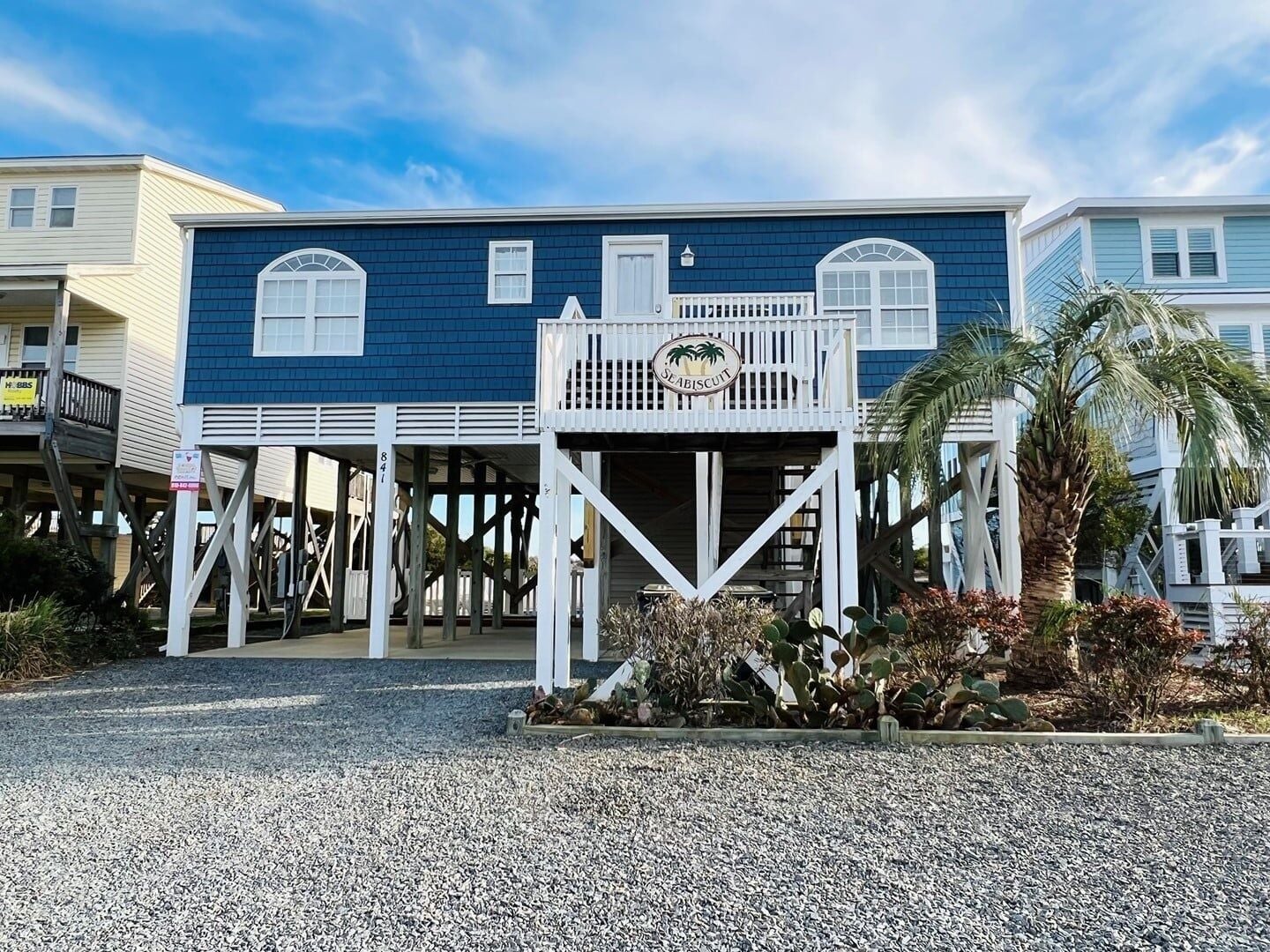 A coastal building with a blue exterior, a white balcony, and a sign reading 'Seabiscuit.'