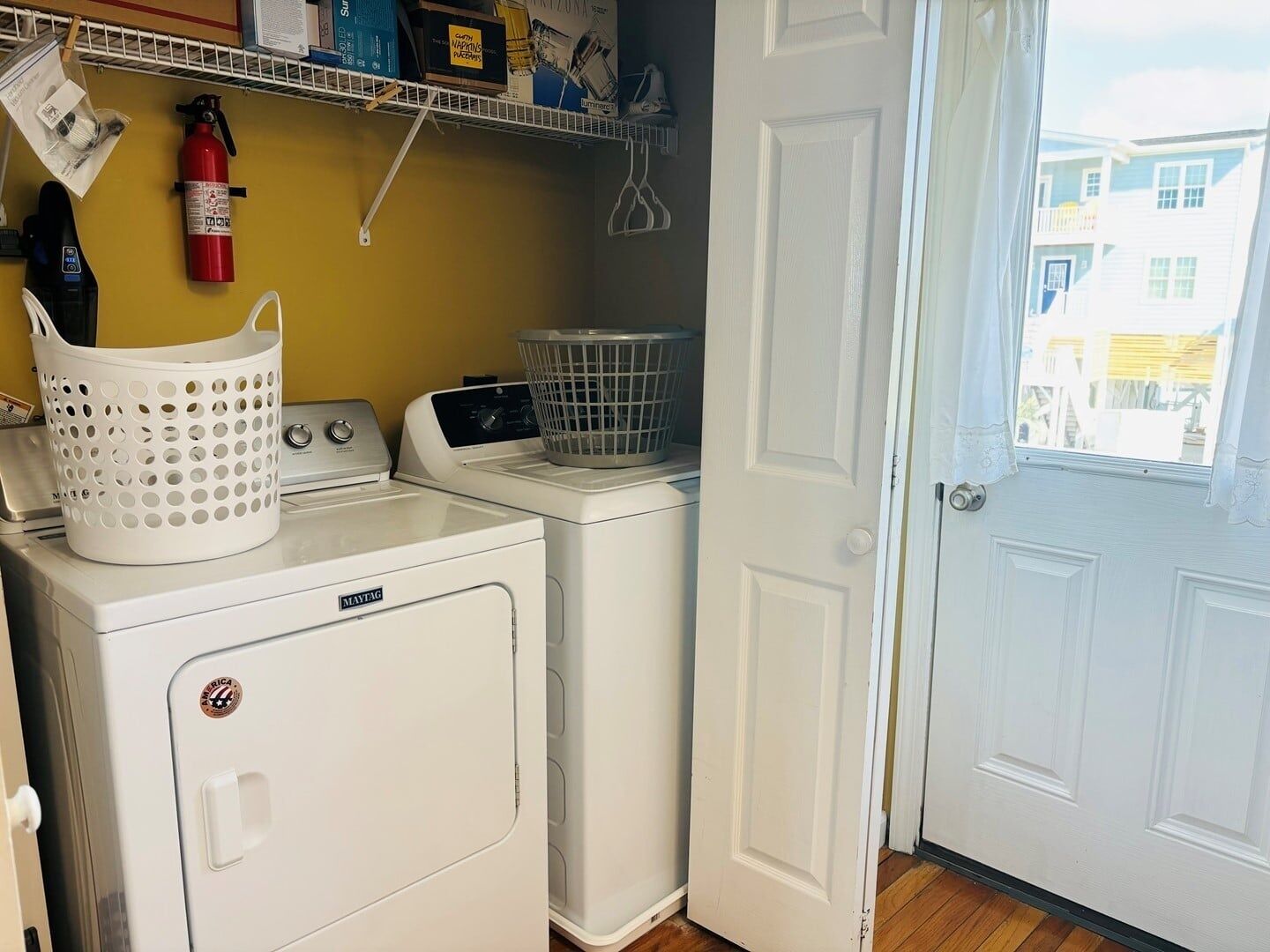A laundry area with a Maytag washer and dryer, a white basket, and a fire extinguisher on the wall.