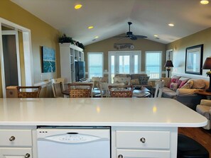A spacious kitchen with a central island, dining area with chairs, and a living room with a sofa and a television. - Sea Biscuit - 4 Br Home (Supply)