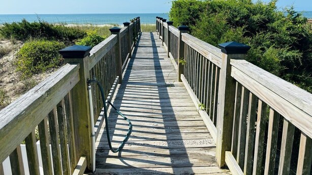 A wooden boardwalk leading to a beach with a clear view of the ocean.