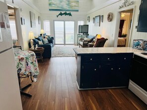 A spacious kitchen with a central island, a dining area with a table and chairs, and a living room with a sofa and a television.