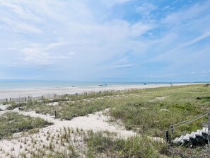 A beach with a wooden fence, grassy dunes, and a pier in the distance. - Seaside - 4 Br Home (Supply)