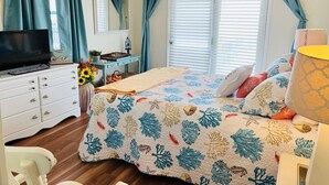 Un dormitorio con cama, televisor, escritorio y ventana con cortinas.
