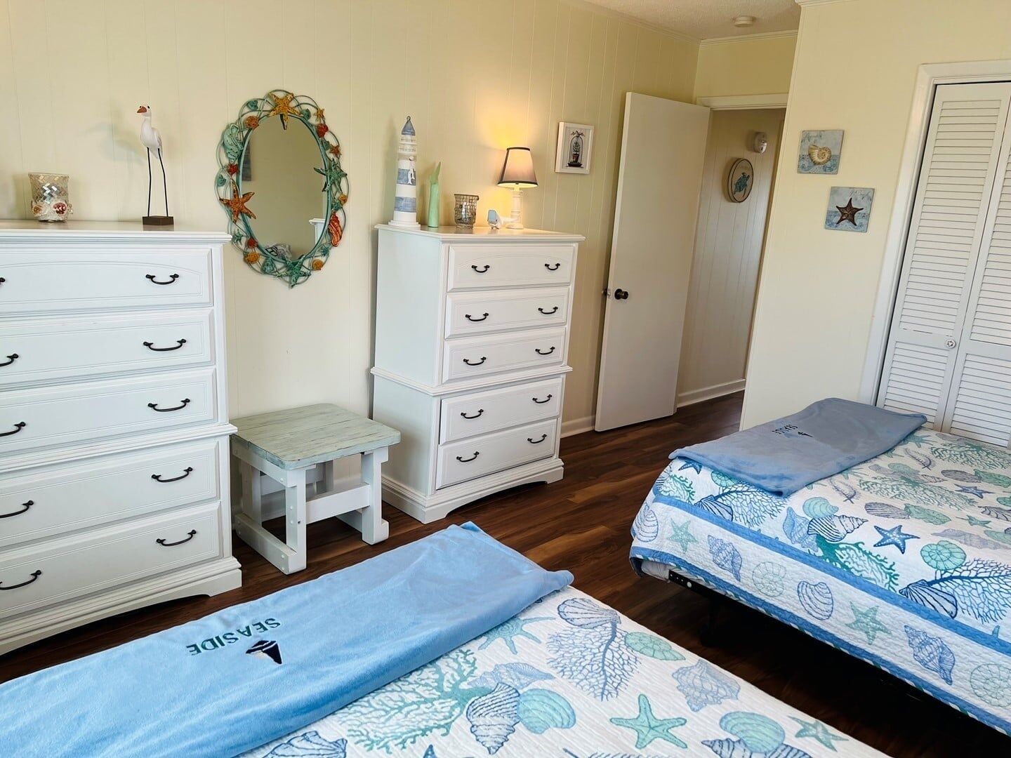 Un dormitorio con cama, cómoda, mesita de noche, espejo y puerta.
