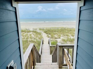Una escalera de madera que conduce a una playa con una vista despejada del océano.