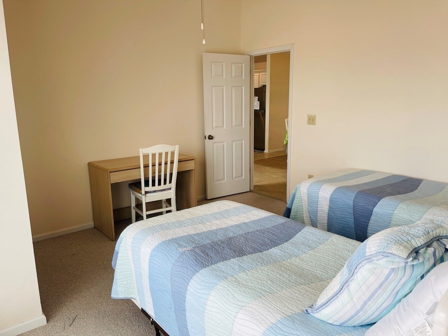 A bedroom with two beds, a desk, and a chair.
