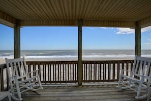 A wooden deck with two rocking chairs facing a beach. - Serenitee - 2 Br Home (Supply)