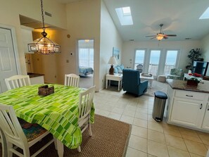 Relax in this spacious living area with a dining table for four, modern kitchen, and ocean views from the balcony.