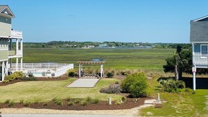 A residential property with a two-story house, a covered patio, and a view of a large open field. - Serenity's Star 4 Bedroom Home by RedAwning (Supply)