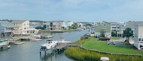 A waterfront property with a dock, boats, and houses along the water.