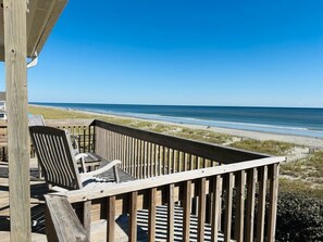 A wooden deck with chairs overlooking a beach.