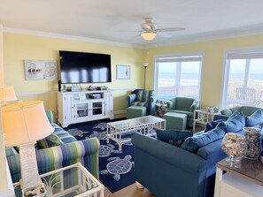 A living room with a television, seating, and a view of the beach. - Summer Sandcastle 5 Bedroom Home by RedAwning (Supply)
