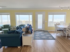 A living room with a sofa, a coffee table, and a dining area with chairs. - Summer Sandcastle 5 Bedroom Home by RedAwning (Supply)