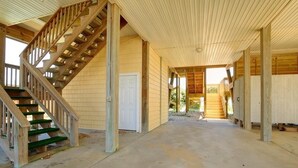 A covered outdoor area with a wooden staircase leading to a door, surrounded by wooden walls and columns.
