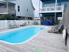 A swimming pool with a wooden deck, lounge chairs, and a slide leading to a second-story deck. - Sunny Times 4 Bedroom Home by RedAwning (Supply)