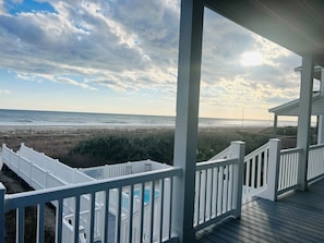 A beachfront property with a wooden deck, a pool, and a view of the ocean.