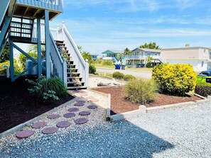 A residential area with a staircase leading to a porch, a driveway with stepping stones, and a well-maintained garden.