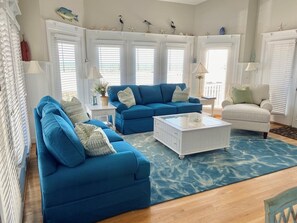A living room with a blue sofa set, a white coffee table, and a light-colored armchair.
