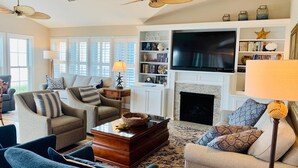 A living room with a fireplace, a television, and a bookshelf. - The Seventh Day 6 Bedroom Home by RedAwning (Supply)