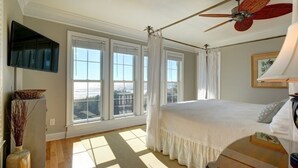 A bedroom with a bed, a ceiling fan, a television, and large windows. - The Seventh Day 6 Bedroom Home by RedAwning (Supply)