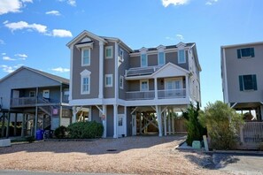 A multi-story building with a balcony, a covered entrance, and a gravel driveway. - The Seventh Day 6 Bedroom Home by RedAwning (Supply)