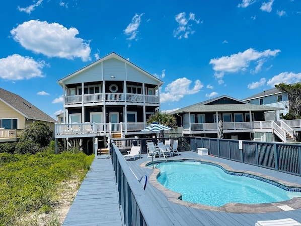 A multi-story building with a pool, deck, and outdoor seating area.
