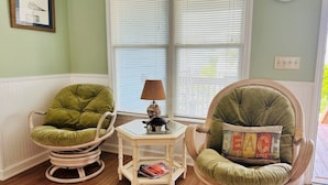 Two green upholstered chairs, a small table with a lamp, and a framed picture on the wall.