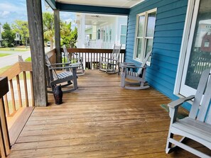 A wooden deck with rocking chairs and a wooden bench.