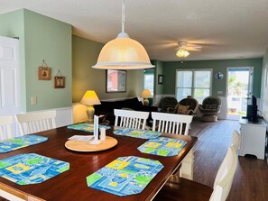 A dining area with a wooden table, white chairs, and blue placemats.
