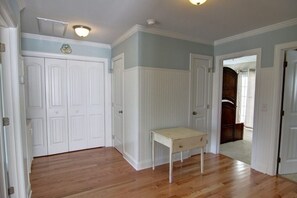 A room with wooden flooring, white paneled walls, and a small table. - Welcome  4 Bedroom Home by RedAwning (Supply)
