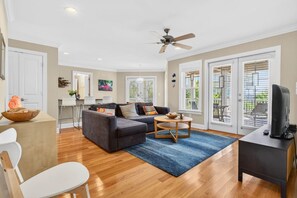 A modern living room with a sofa, coffee table, and TV stand. - Windsong - 5 Br Home (Supply)