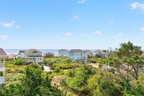 A coastal residential area with houses, a beach, and a clear sky. - Windsong - 5 Br Home (Supply)