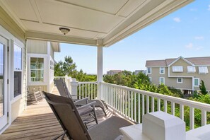 A covered outdoor area with a wooden deck, white railings, and a view of neighboring houses.