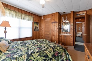 A bedroom with a bed, a dresser, a mirror, and a window with blinds. - Yellow Bird 2 Bedroom Home by RedAwning (Supply)